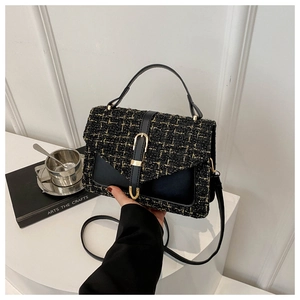 Détail du sac bandoulière en tweed et cuir avec fermoir doré tenu à la main