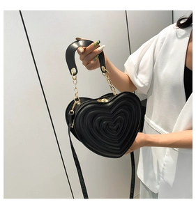 Detail der schwarzen herzförmigen Handtasche mit Prägung und goldener Kette