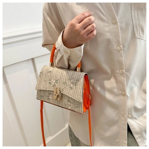 Detail of woven straw handbag with floral embroidery and orange leather strap