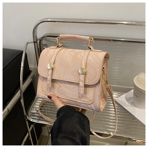 Détail du sac à main rose clair à motif marbre avec boucles dorées et poignée haute