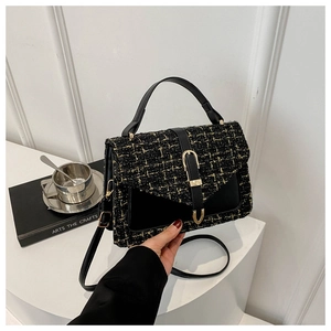 Vue détaillée de la texture en tweed noir et doré d'un sac à main structuré à boucle dorée