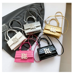 Detail view of five shiny croc-effect handbags in silver, gold, white, pink and black colors