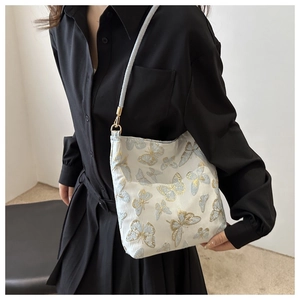 Detailed embroidery of gold and blue butterflies on a minimalist white crossbody bag