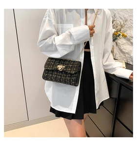 Close-up of black tweed fabric texture and gold rotating twist lock on a shoulder bag