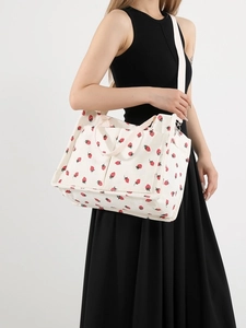 White corduroy strawberry print tote bag with adjustable shoulder strap on a model