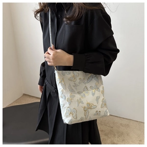 Detail of blue and gold butterfly embroidery on white canvas jacquard crossbody bag