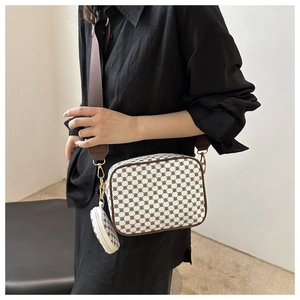 Detail of crossbody bag featuring printed patterns with a matching round coin purse charm