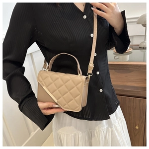 Modern beige quilted crossbody bag with gold hardware shown on a model in a minimal room
