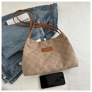 Detail of khaki woven texture tote bag with brown leather straps and fashion patch
