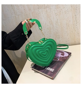 Detailansicht der herzförmigen grünen Ledertasche mit Steppmuster und goldener Kette