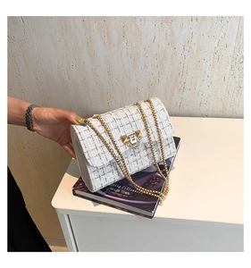Close-up of white tweed shoulder bag with gold chain strap and metallic lock detail