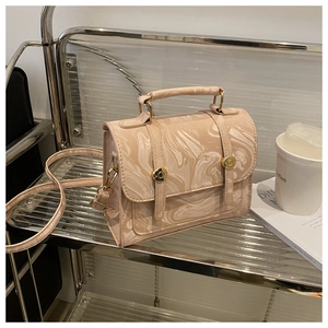 Détail du sac à main beige motif marbre avec boucles dorées et lanières décoratives