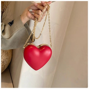 Detail of a red heart-shaped hard case handbag with chunky gold chain strap