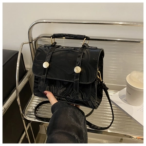 Détail d'un sac à main noir texture marbre avec boucles dorées sur présentoir métal