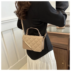 Detail of quilted beige crossbody bag with gold metal trim and adjustable strap