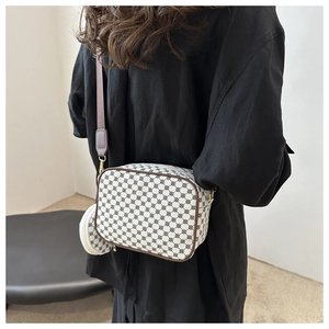 Close-up of stylish printed crossbody bag with wide shoulder strap and round coin purse