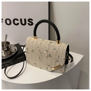 Detail of hand-woven beige bag with floral embroidery and gold metal clasp hardware