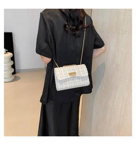 Detailed close-up of white tweed shoulder bag with gold chain strap on a model