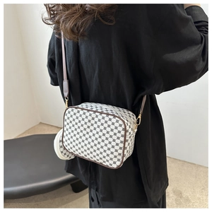 Detail of vintage geometric print crossbody bag with brown leather trim and gold hardware