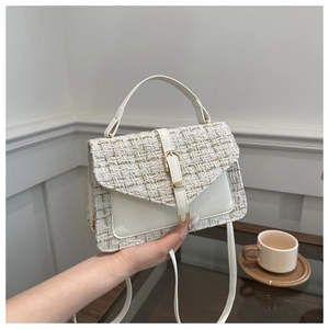 Détail du sac à main en tweed blanc avec un fermoir métallique doré en forme de U