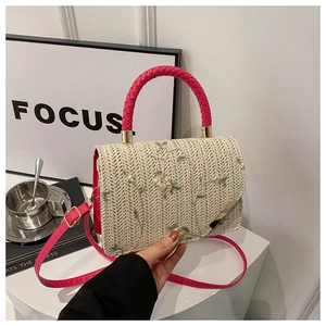 Detailed close-up of straw woven bag featuring floral embroidery and pink rope handle
