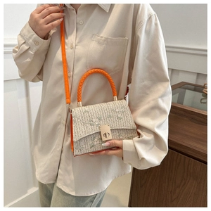 Straw crossbody bag with floral embroidery and orange strap shown on a person