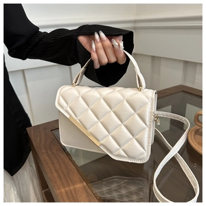 Detail shot of white quilted crossbody bag with gold metal trim and smooth top handle