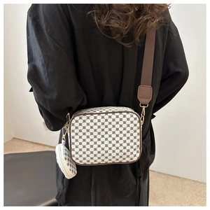 Detail of vintage patterned crossbody bag with wide strap and round coin purse pendant