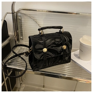 Détail du sac à main à motif marbre noir, finition brillante et boucles dorées