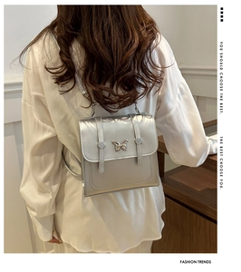 Detail of silver metallic mini backpack with butterfly accent and polished mirror finish