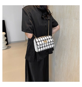 Close-up of black and white tweed crossbody bag with gold chain strap on model