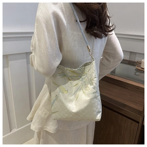 Close-up of golden silk embroidery and bamboo leaf patterns on a modern bucket bag
