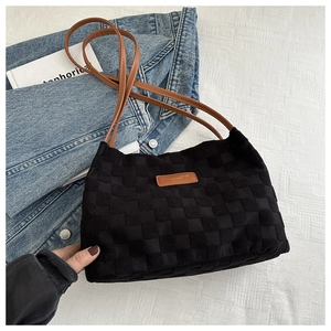 Detail of black woven tote bag with brown straps and leather fashion label decoration