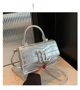 Detail of silver crocodile-embossed faux leather handbag with metallic logo and strap