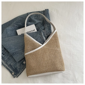 Detail of woven straw bucket bag with white leather trim on neutral linen background