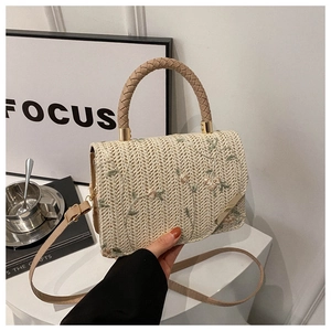 Detail of cream woven handbag featuring delicate floral embroidery and gold hardware