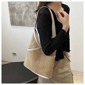 Detailed close-up of woven straw tote bag with elegant white leather shoulder strap detail