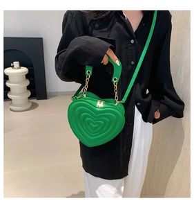 Detail der leuchtend grünen herzförmigen Tasche mit 3D-Nähten und goldener Kette