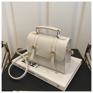 Détail du sac blanc en cuir gaufré avec boucle dorée sur un décor minimaliste chic