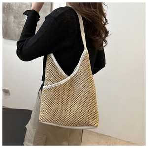 Detail view of handmade straw bucket bag with white trim and hollow woven texture