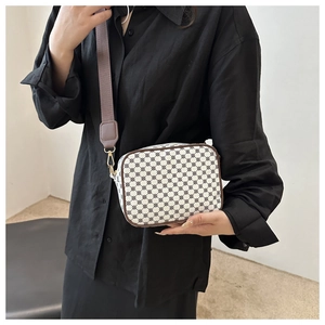 Close-up of retro print canvas handbag with wide brown strap and gold metal hooks
