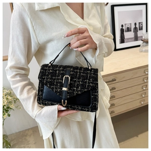 Detailed view of black and gold tweed shoulder bag with leather strap and metal hardware