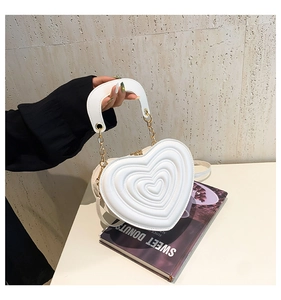 Detail der weißen herzförmigen Handtasche mit Wellenstruktur und goldener Kette