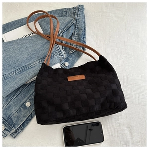 Detail of black checkerboard woven tote bag with brown straps and stylish layout