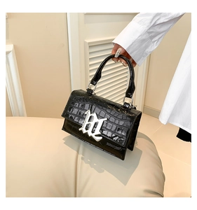 Detail of glossy black crocodile pattern on square handbag with silver Gothic B hardware