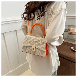 Detail of beige woven crossbody bag featuring pink floral embroidery and bright orange handles