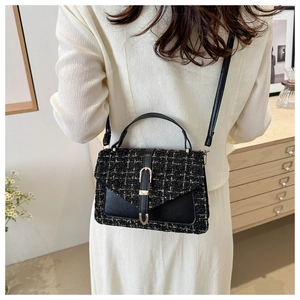 Close-up of black and gold tweed crossbody bag worn by a model in a cozy indoor setting