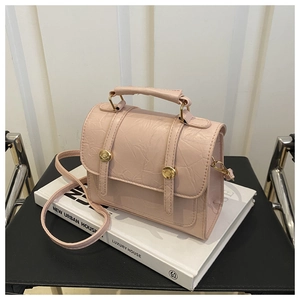 Détail d'un sac à main rose pâle style ballet en cuir texturé avec boutons dorés