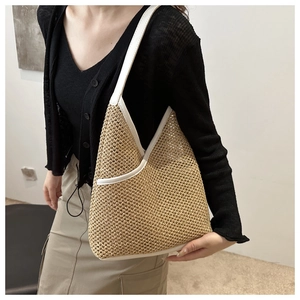 Detail view of woven straw tote bag with white leather straps shown on a female model
