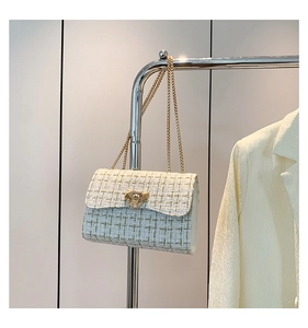 Detail of tweed crossbody bag with golden chain strap and metallic flip-lock closure